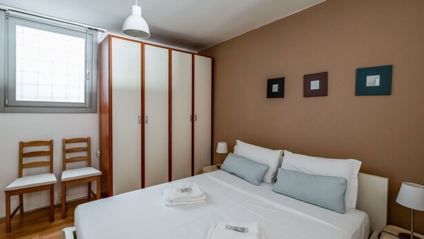 Une chambre à coucher avec un lit, deux chaises, une armoire et une fenêtre.