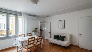 Une pièce comprenant une table à manger, des chaises, un canapé, une porte et une fenêtre.