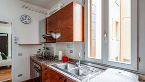 Une cuisine moderne avec des meubles en bois, un évier à deux bacs et une fenêtre qui laisse entrer la lumière naturelle.