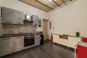 A modern kitchen with grey cabinets, a tiled backsplash, and a wooden ceiling.