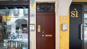Una façana amb una porta marró, amb el número 48, i un senyal que indica que és un lavabans públic.
