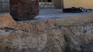 Un edificio con facciata piatta, diverse finestre e un grande masso in primo piano.