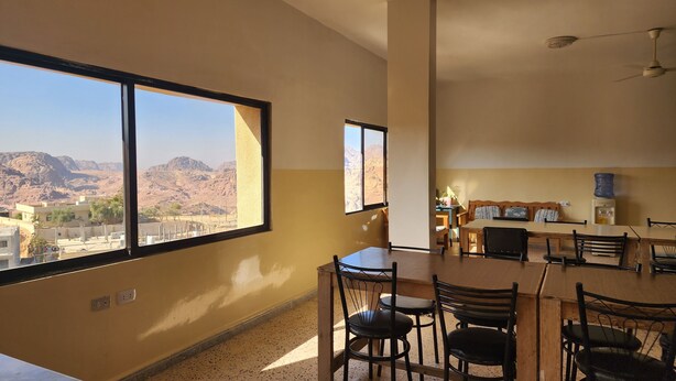 Una stanza con un'ampia finestra che offre vista su montagne e edifici. È presente una zona pranzo con tavolo e sedie.