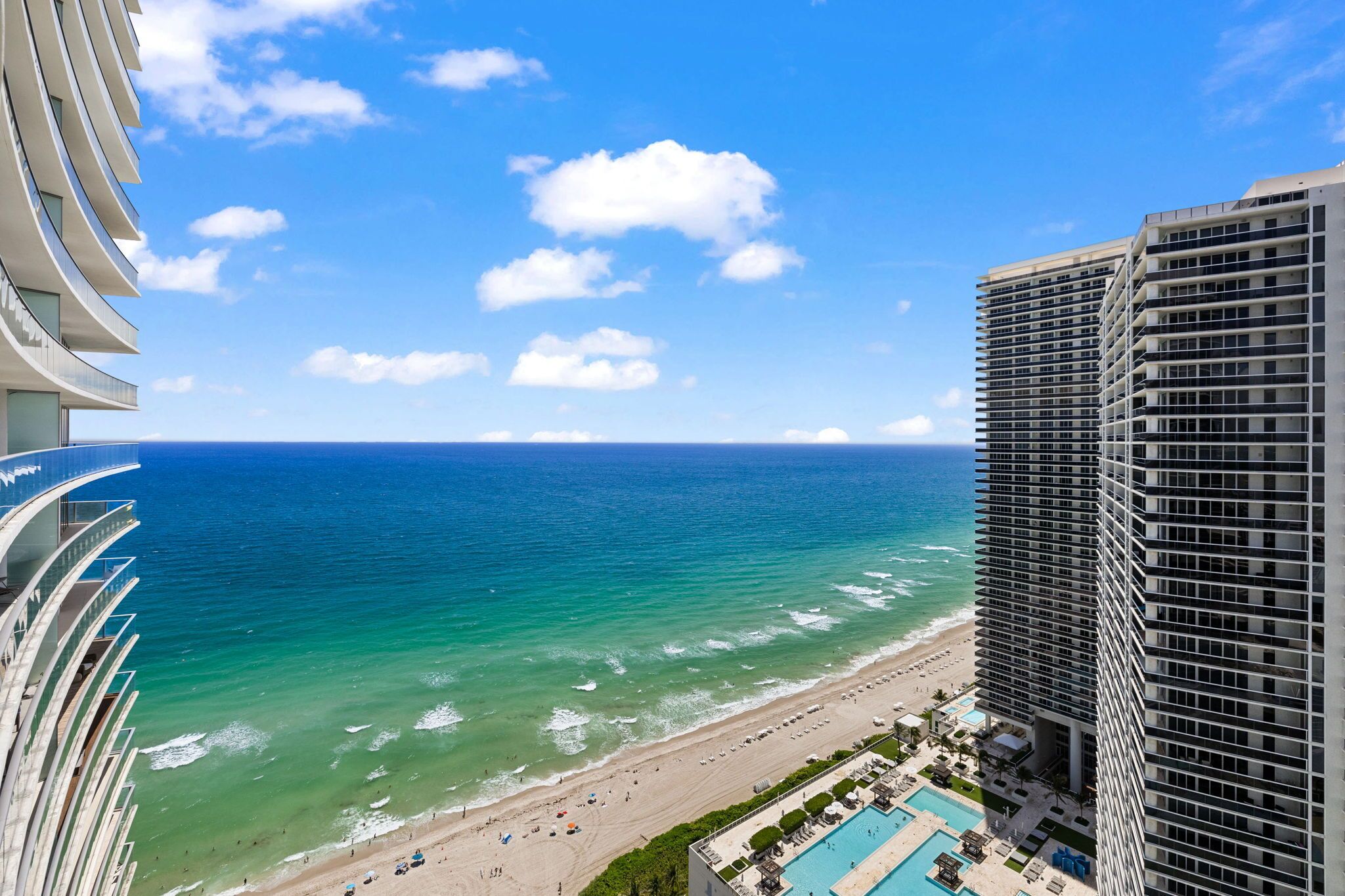 A high-rise hotel with a view of the ocean and beach.