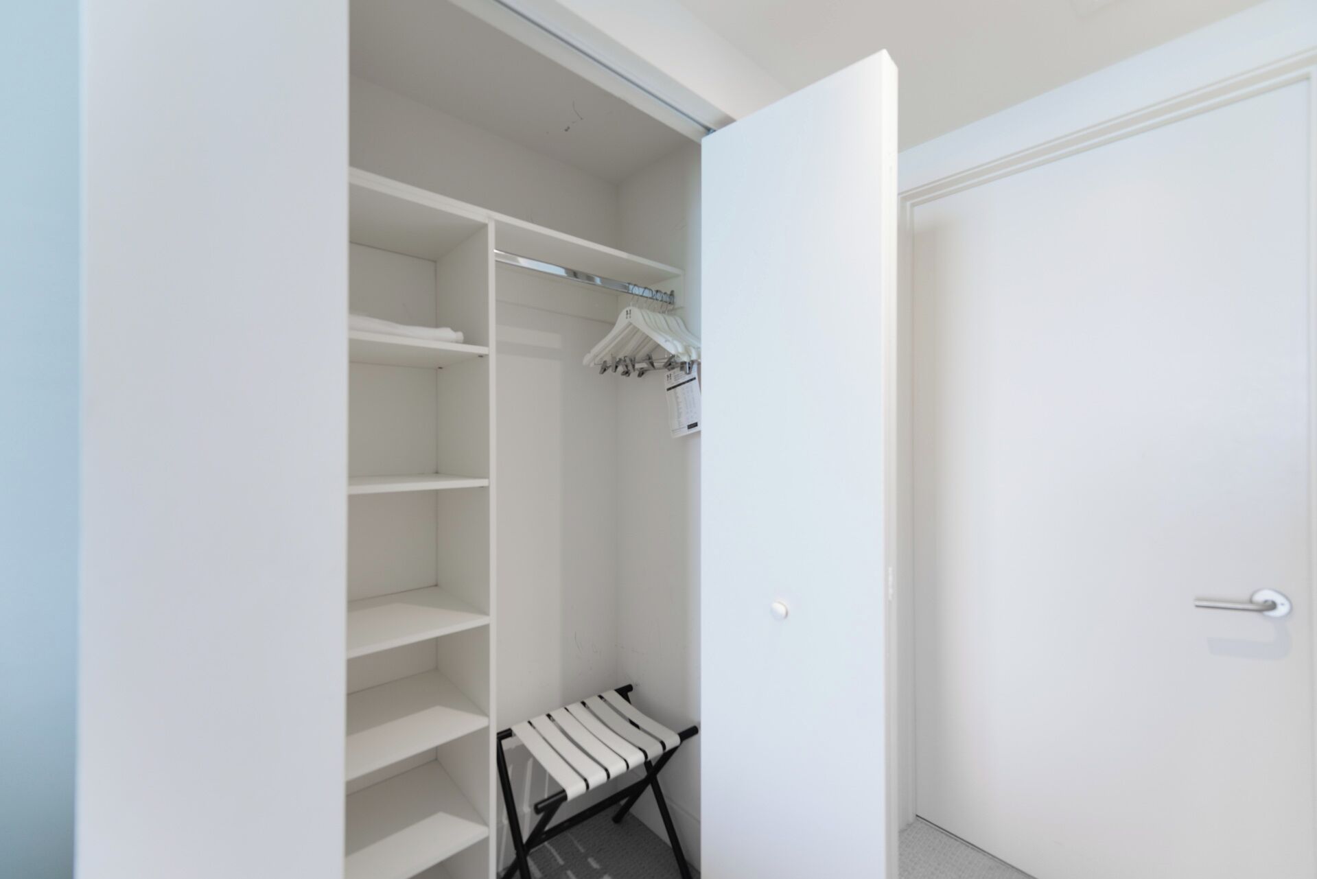 Ein begehbarer Kleiderschrank mit offenen Regalen, einer Kleiderstange und einer Bank.