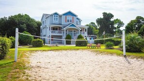 A two-story house with a balcony, a tennis court, and a well-maintained lawn. - Duck Location! Volleyball, Pool, Game Room & More (Duck)