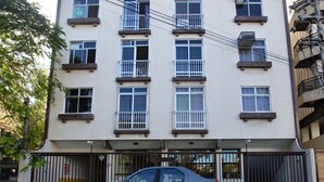 A multi-story residential building with a car parked in front. - Mar Doce Lar (Cabo Frio)