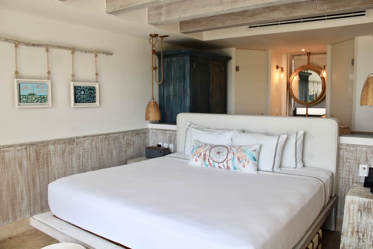 Une chambre à coucher avec un grand lit, une armoire, une table de chevet et un miroir.
