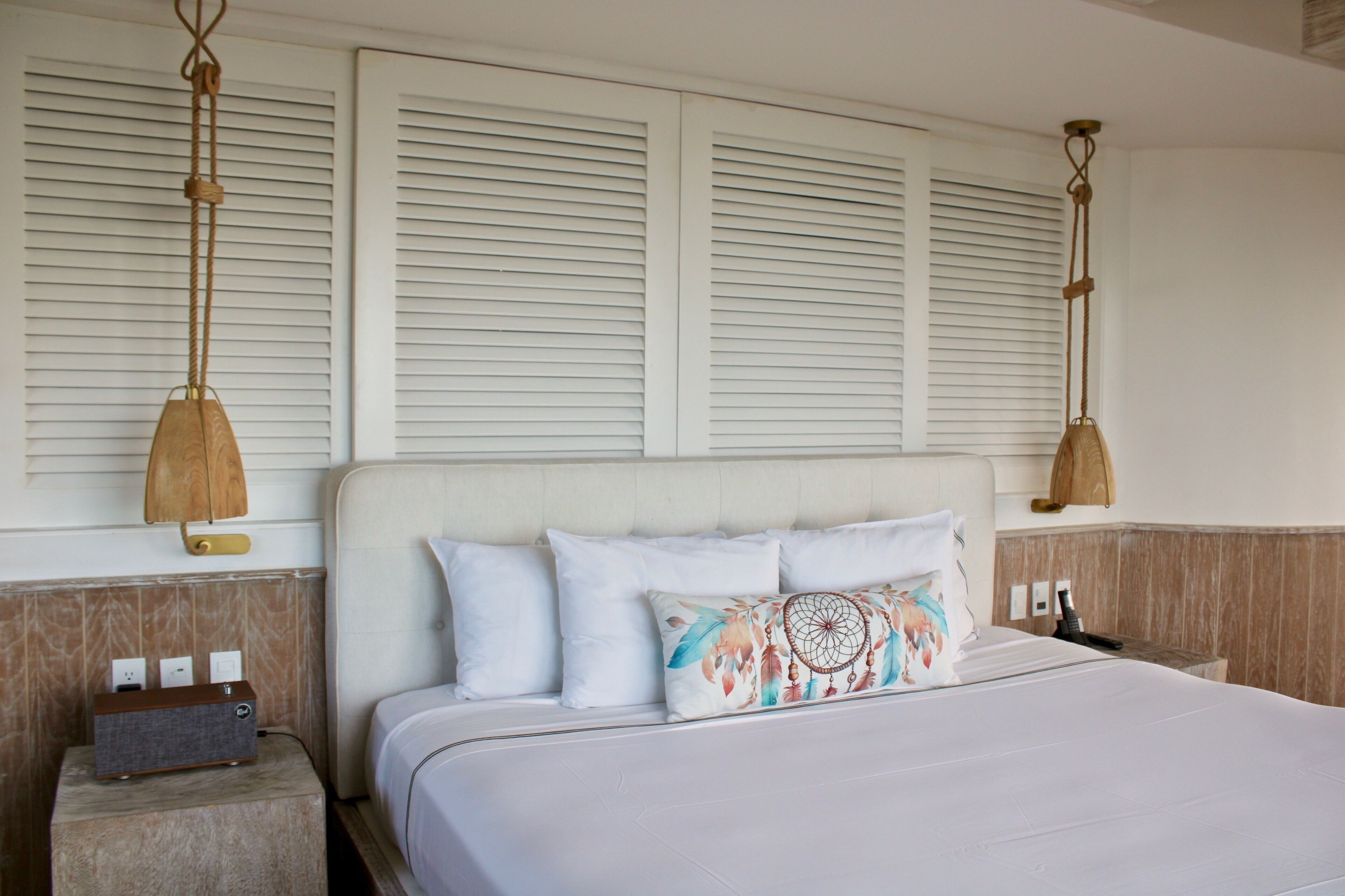 A hotel room with a bed, bedside tables, and a wall-mounted lamp.