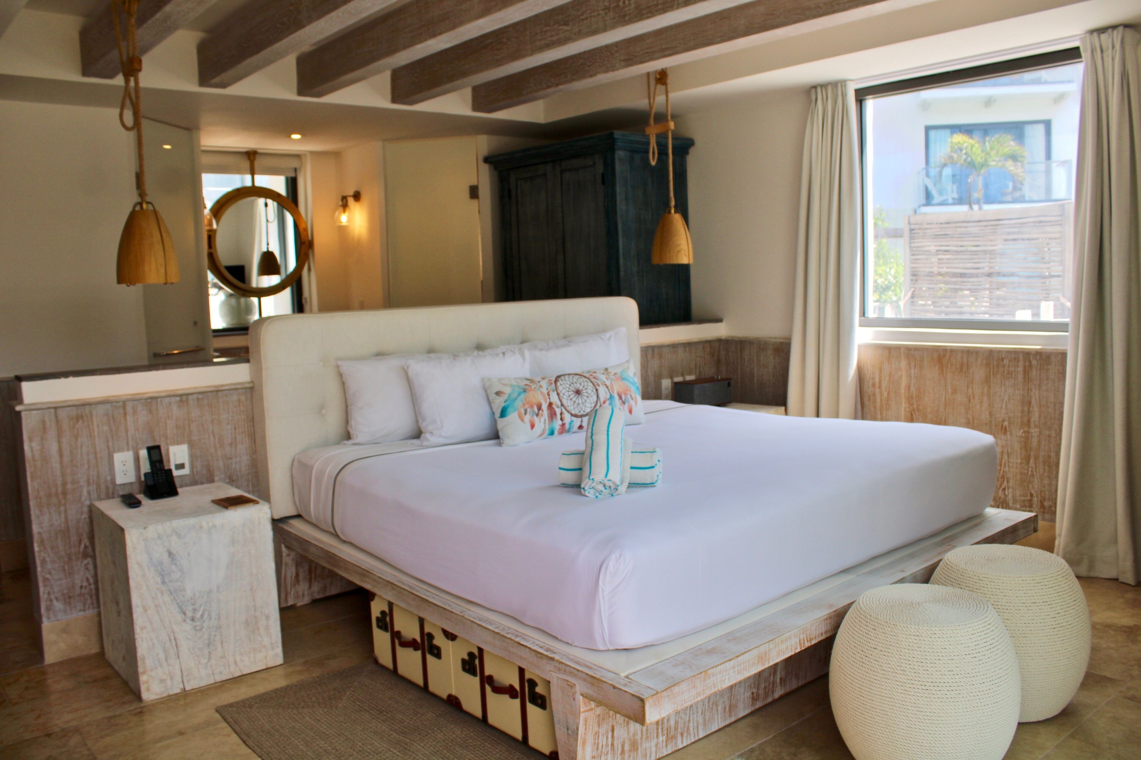 Une chambre à coucher avec un grand lit, des tables de chevet, une armoire et une fenêtre avec des rideaux.