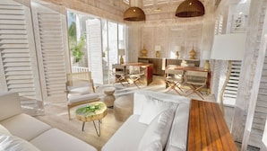 Amplia sala de estar con una mesa de centro de madera, sofás blancos y una mesa de comedor con sillas.
