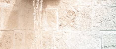 A couple embracing in a shower with water flowing from a wall-mounted fixture.