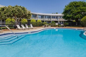 Une piscine avec des chaises longues et un bâtiment en arrière-plan.