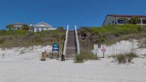 Trappe fører ned til et strandområde, med skilt der angiver adgang til stranden.