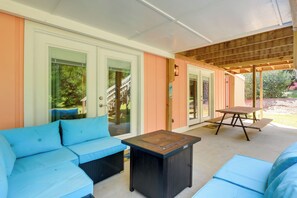 A covered patio area with a blue sofa, a small table, and a bench. - Emerald Isle Vacation Rental, Walk to Beach! (Emerald Isle)