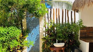 Un jardín con fuente de agua, un bebedero de pájaros de madera y un muro de ladrillo.
