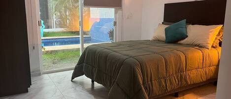 A bedroom with a bed, a sliding glass door leading to a pool, and a dreamcatcher on the wall.