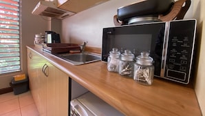 A compact kitchen with a microwave, a sink, and a wooden countertop. - Island Travelers Acccommodation (Suva)