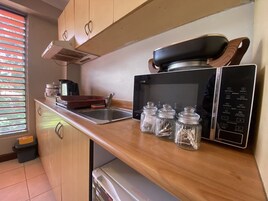Una cocina compacta con microondas, un lavamanos y una encimera de madera.