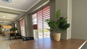 A spacious room with a large wooden table, a potted plant, and a ceiling fan. - Island Travelers Acccommodation (Suva)