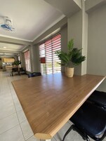 Una habitación amplia con una gran mesa de madera, una planta en maceta y un ventilador de techo.