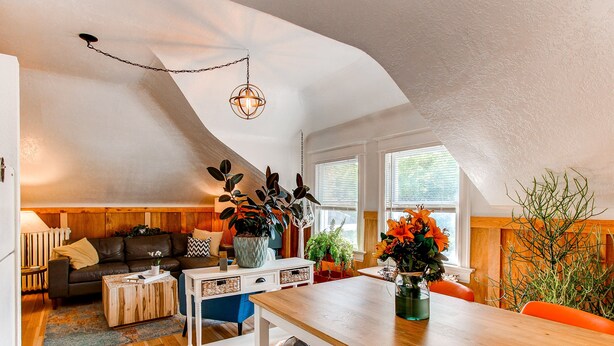 Un espace de vie chaleureux de style loft, comprenant un coin repas, des meubles en bois et une variété de plantes.