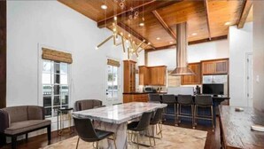 Una cocina moderna con armarios de madera, una isla de mármol e iluminación colgante.