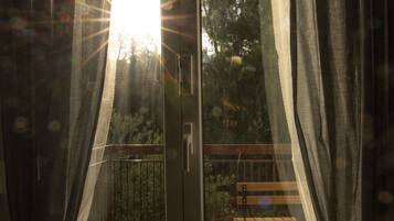 A room with a sliding glass door leading to an outdoor balcony with a wooden bench.