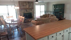 Een ruime woonkamer met een houten eettafel, stoelen, een bank en een televisie.