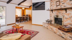 Ein Wohnzimmer mit Kamin, einer Essecke mit Stühlen und einem großen Fenster.
