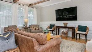 Ein Wohnzimmer mit einer Couch, Sesseln, einem Couchtisch und einem an der Wand befestigten Fernseher.