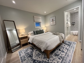 Ein modernes Schlafzimmer mit einem großen Bett, Nachttischlampen, einem Spiegel und einem gemusterten Teppich.