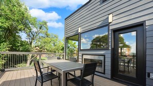 Eine Terrasse mit Tisch und Stühlen, einem Grill und Blick auf die Umgebung.