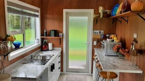 Une cuisine dotée d’un plan de travail en marbre, d’un évier et d’une porte donnant sur un jardin.