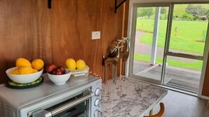 Une cuisine dotée d’un plan de travail en marbre, d’un four encastré et offrant une vue sur une pelouse verdoyante grâce à une porte-fenêtre coulissante.