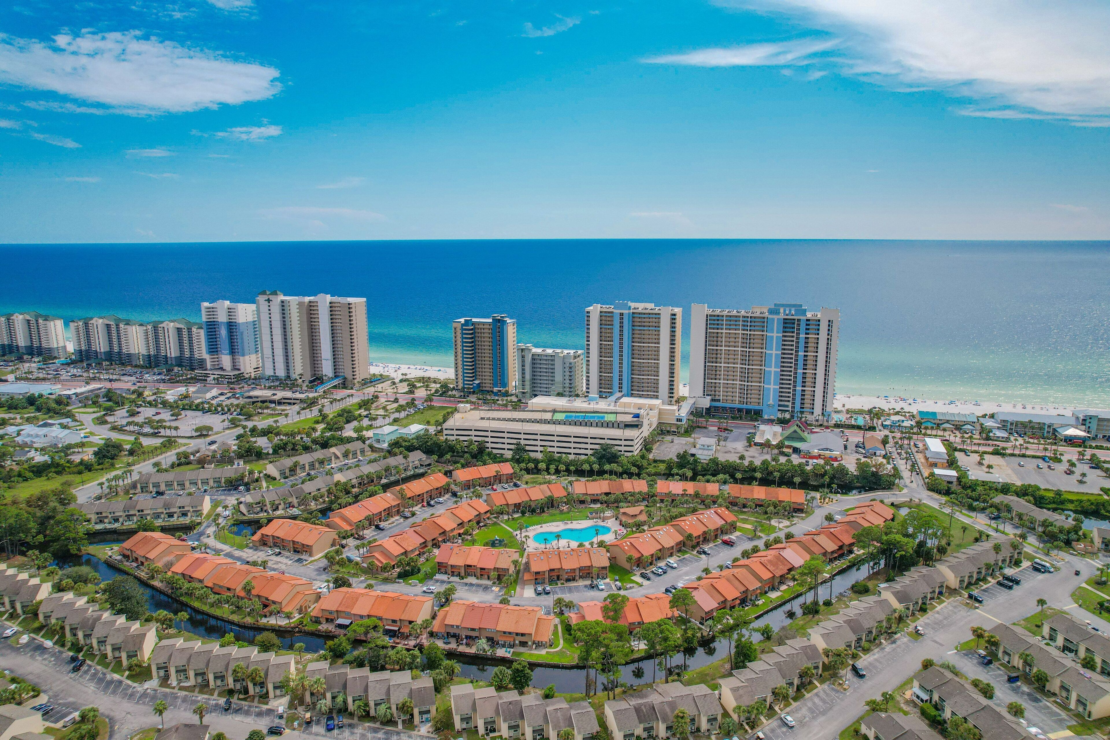 A coastal resort with high-rise buildings, a central pool, and a marina.
