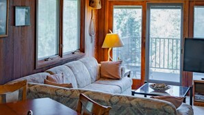 A cozy cabin interior with a wooden ceiling, a sofa, a dining table, and a TV. - Mountain-View Condo with fireplace, pool, hot tub, and ski access. (Durango)