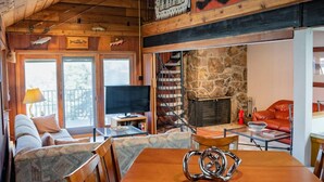 A cozy cabin interior with a wooden dining table, chairs, a sofa, a TV, and a fireplace. - Mountain-View Condo with fireplace, pool, hot tub, and ski access. (Durango)
