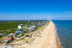 An aerial view of a coastal area with houses, a beach, and a lighthouse. - Absolute Searenity- Oceanfront, Pet-Friendly, Private Pool and Hot Tub (Nags Head)