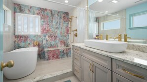 A bathroom with a bathtub, a shower, and a large mirror.