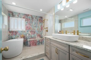 A bathroom with a bathtub, a shower, and a large mirror.