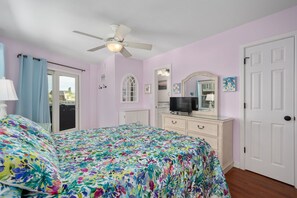 A bedroom with a bed, a dresser, a television, and a ceiling fan. - Absolute Searenity- Oceanfront, Pet-Friendly, Private Pool and Hot Tub (Nags Head)