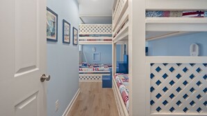 A narrow hallway with bunk beds on one side and a door on the other.