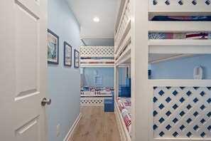 A narrow hallway with bunk beds on one side and a door on the other.