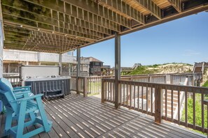 A covered deck with a hot tub and chairs, overlooking a beach and buildings. - Absolute Searenity- Oceanfront, Pet-Friendly, Private Pool and Hot Tub (Nags Head)