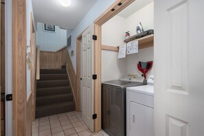 A compact kitchen with a washing machine, a drying rack, and a small countertop. - Absolute Searenity- Oceanfront, Pet-Friendly, Private Pool and Hot Tub (Nags Head)
