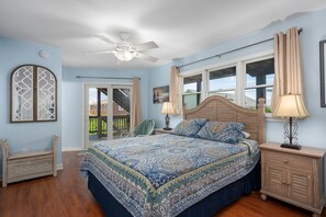 A bedroom with a bed, a nightstand, a chair, a ceiling fan, and a window with curtains. - Absolute Searenity- Oceanfront, Pet-Friendly, Private Pool and Hot Tub (Nags Head)