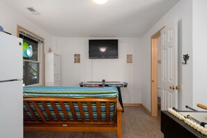 A compact room with a bed, a TV, a small kitchenette, and a door. - Absolute Searenity- Oceanfront, Pet-Friendly, Private Pool and Hot Tub (Nags Head)