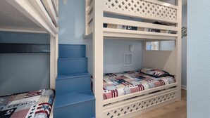 A bunk bed with a ladder, a small window, and a door.