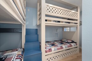 A bunk bed with a ladder, a small window, and a door.